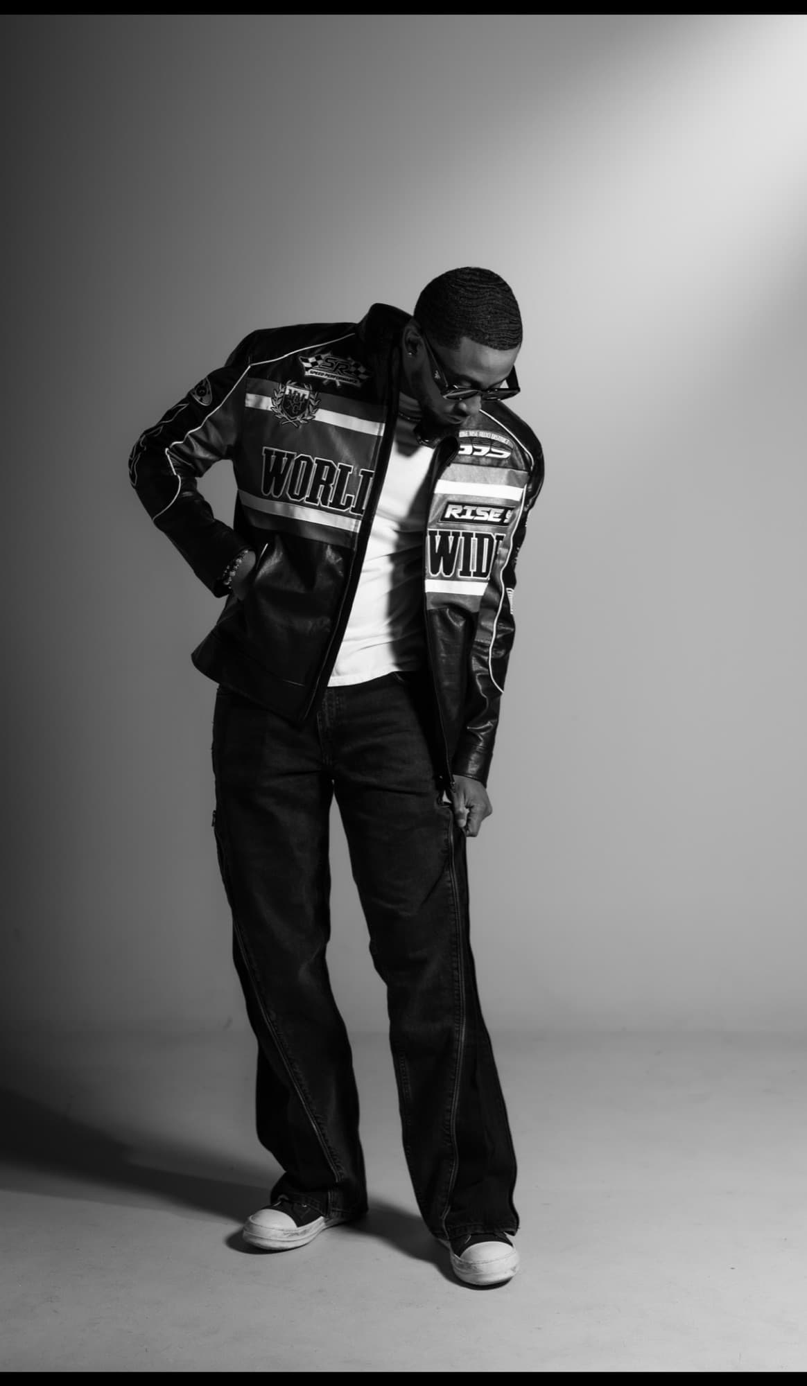 Bryce in a black and white studio portrait wearing a racing jacket, looking down