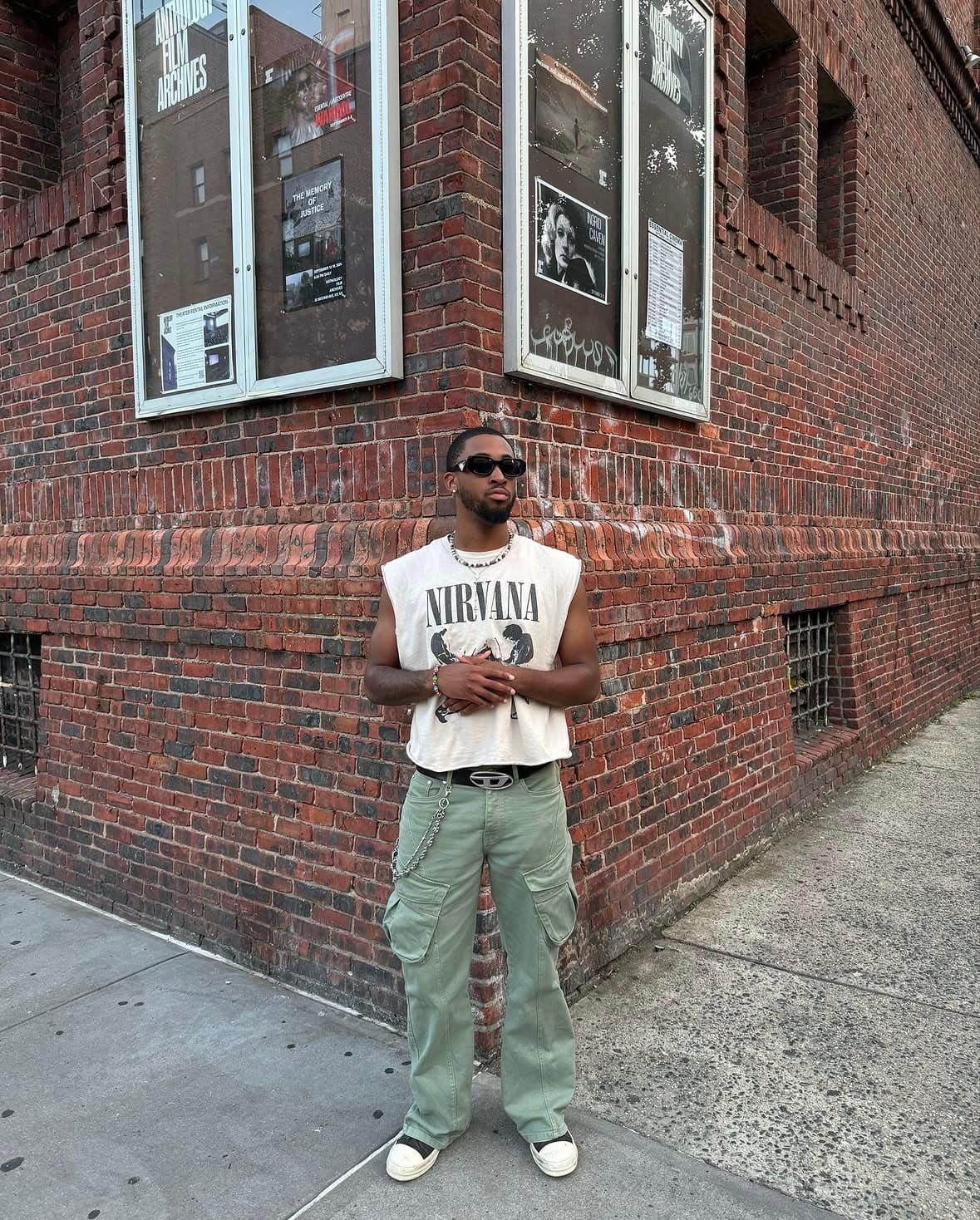 Bryce in a Nirvana tee and green cargo trousers on a brick corner