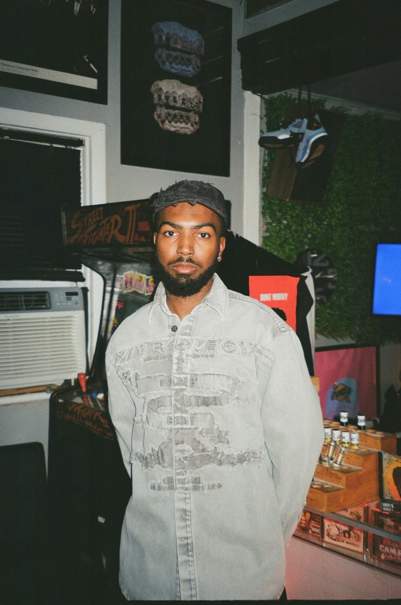 Khi in a washed denim shirt in front of a Street Fighter II arcade cabinet